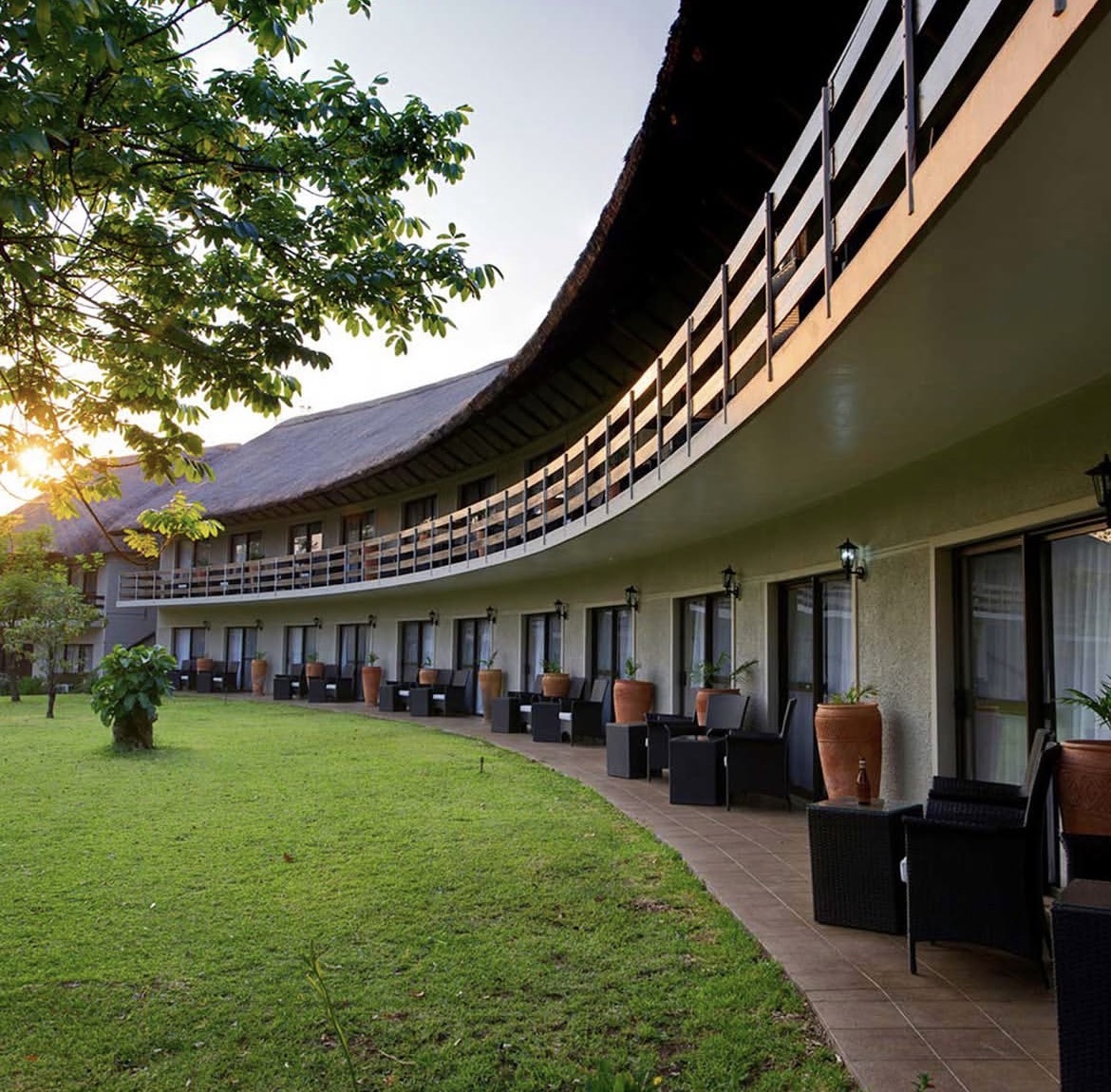 Thatched conference lodge with balcony rooms overlooking a green lawn